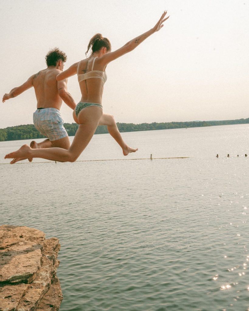 Two friends jump into the lake on a sunny day.